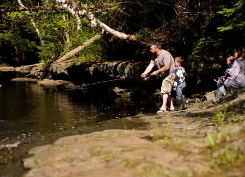 un homme et un enfant pêchant dans une rivière dans l'établissement Rocky Brook Acres, à Cormack