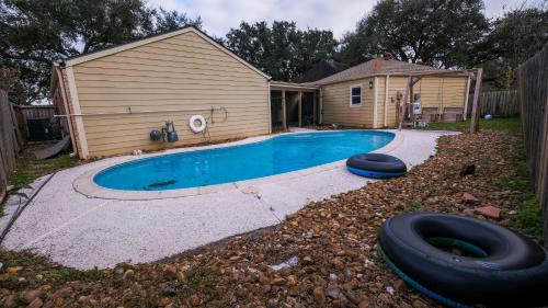 uma piscina com um pneu ao lado de uma casa em Pool House, 20 Minutes from DT 4BDR for 10 Guests - Winkleman em Houston