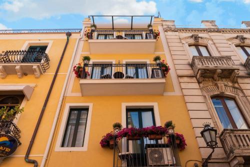 un edificio giallo con balconi e fiori di Valentina a Taormina