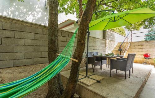 a hammock is tied to a tree in a backyard at 2 Bedroom Cozy Apartment In Omisalj in Omišalj