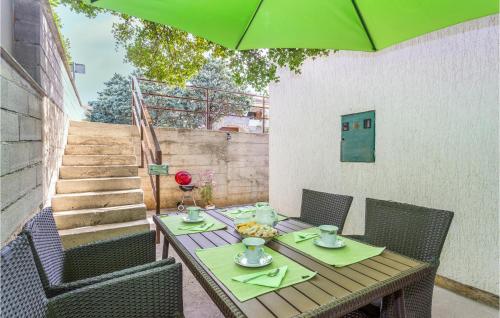 a wooden table with chairs and a green umbrella at 2 Bedroom Cozy Apartment In Omisalj in Omišalj