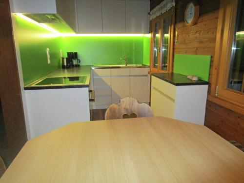 a kitchen with green walls and a wooden table at Holiday home in Sibratsgf ll in the Bregenzerwald in Sibratsgfäll