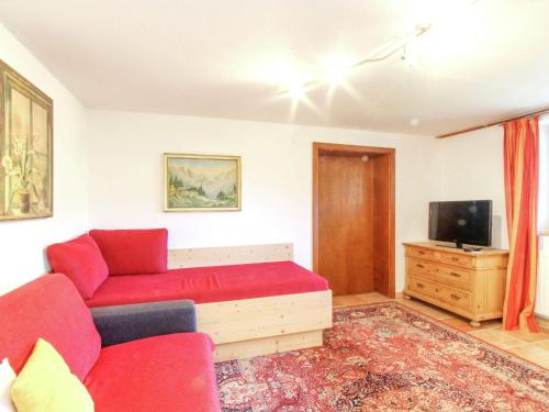 salon z czerwoną kanapą i telewizorem w obiekcie Chalet in Kufstein near Ski School w mieście Niederndorferberg