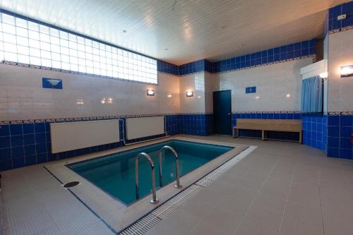 a swimming pool in a bathroom with blue tiles at AMAKS Safar Hotel in Kazan