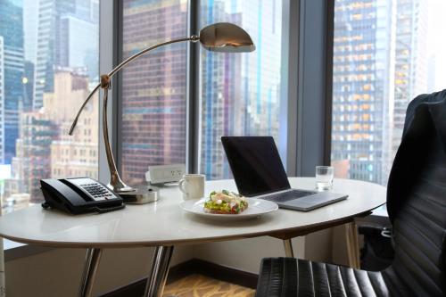 a desk with a laptop and a plate of food on it at InterContinental New York Times Square by IHG in New York