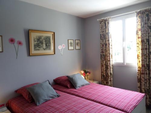 a bedroom with a large bed with pink sheets and a window at Les Broussous in Sauve
