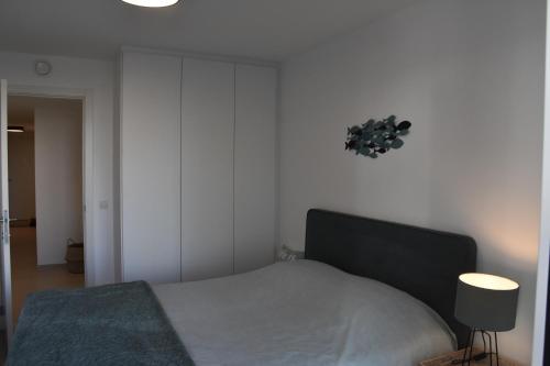 a bedroom with a bed and a clock on the wall at Lichtrijk 2-slaapkamerappartement met zeezicht en gratis parking in Ostend