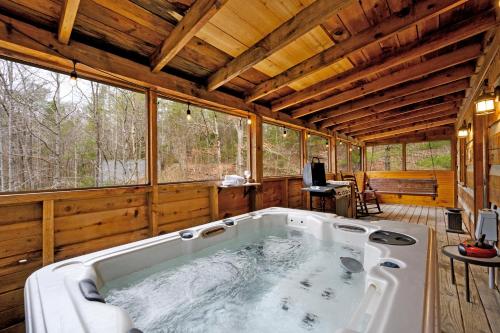 a large tub in the middle of a room with windows at The Robins Nest with hot tub in Pigeon Forge