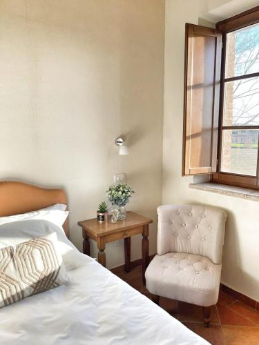 a bedroom with a bed and a chair and a window at Hotel More di Cuna in Monteroni dʼArbia