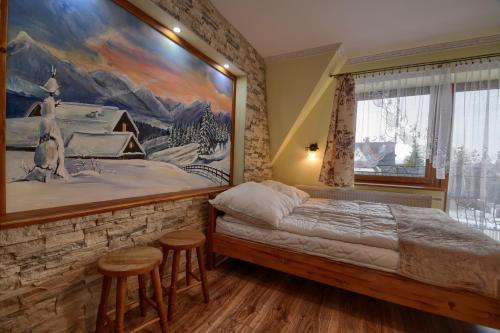 a bedroom with a bed with a painting on the wall at Willa Laskosia in Murzasichle