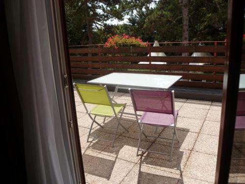three chairs and a table on a patio at Logis Hôtel Restaurant Le Chalet du Mont Roland in Dole