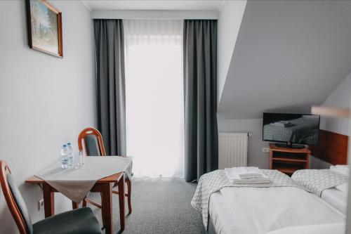 a hotel room with a bed and a table and a tv at Pensjonat Jurkowski Wellness & Spa in Ochotnica Dolna