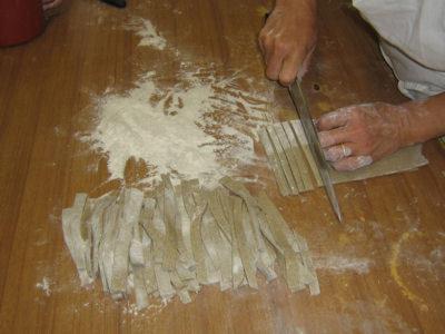 a person cutting up onions on a wooden table at Agriturismo Val Codera in Verceia