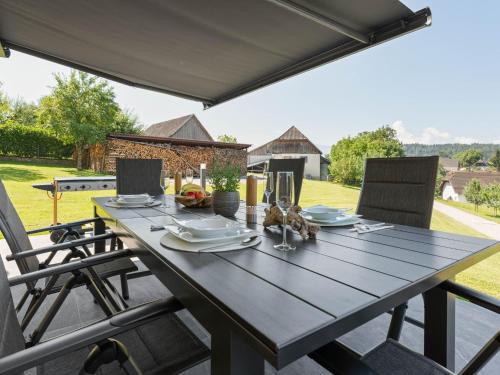 Köttmannsdorf的住宿－Holiday home in Carinthia near Lake Woerthersee，庭院里配有一张带椅子的木桌