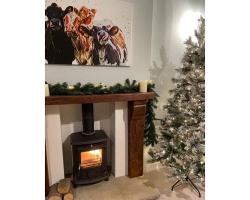 a living room with a fireplace and a christmas tree at Swallow Cottage in Ripon