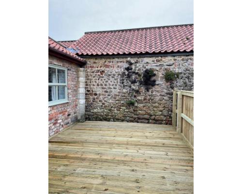 a wooden deck in front of a brick building at Swallow Cottage in Ripon