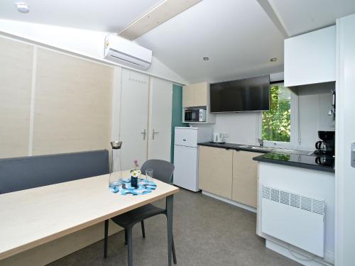 a kitchen with white cabinets and a wooden table at Mobile home in Sachsenburg Carinthia with pool in Sachsenburg