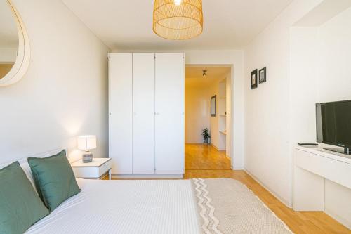 ein weißes Schlafzimmer mit einem Bett und einem TV in der Unterkunft Simplon 10 - Lausanne Gare in Lausanne