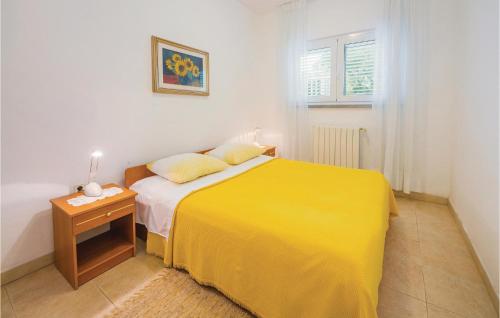 a yellow bed in a white room with a table at Gorgeous Apartment In Rabac With Kitchen in Rabac