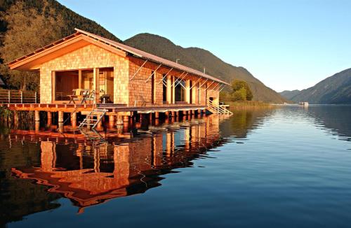 a house on a dock on a body of water at Seehotel Enzian in Weissensee