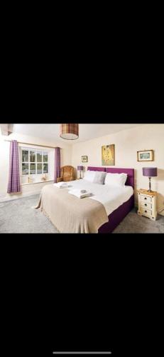 a bedroom with a large bed with purple curtains at The Red Lion in Sedbergh