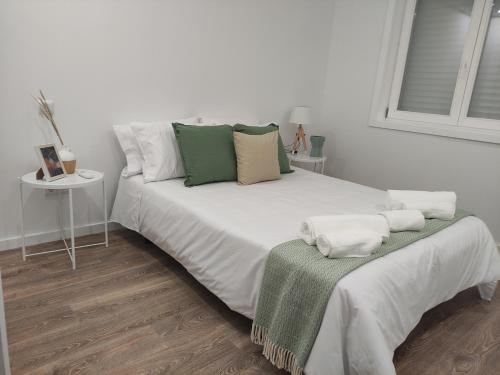 a white bed with green and white pillows on it at Pinheiro Guest House in Ponte de Lima