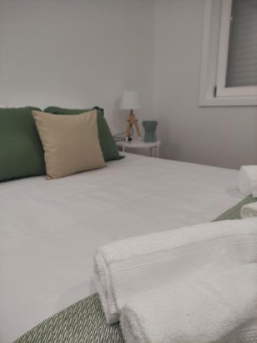 a white bed with green and white pillows on it at Pinheiro Guest House in Ponte de Lima