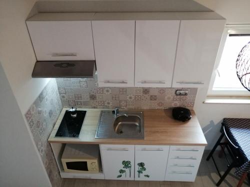 a small kitchen with white cabinets and a sink at Apartment Camerin in Koper