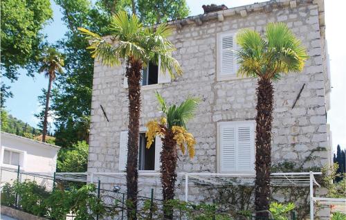 a stone building with palm trees in front of it at Holiday Home Potok Vi in Trsteno