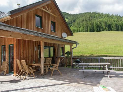 ein Holzhaus mit einem Picknicktisch und Stühlen auf einer Terrasse in der Unterkunft Chalet in Hohentauern Styria with sauna in Hohentauern