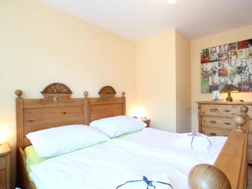 ニーダーンジルにあるApartment in Niedernsill near centreの白いベッド1台(木製ヘッドボード付)が備わるベッドルーム1室が備わります。