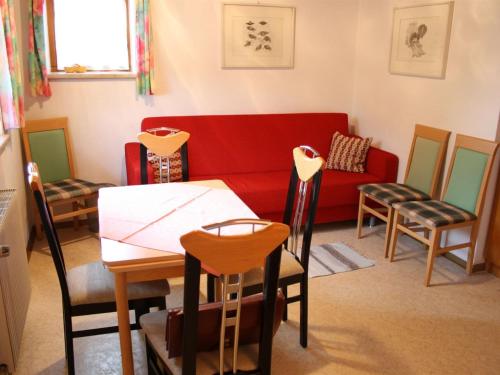 ein Wohnzimmer mit einem roten Sofa, einem Tisch und Stühlen in der Unterkunft Apartment in Tirol close to the ski slopes in Sankt Johann in Tirol
