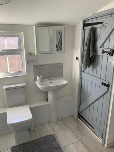 y baño con lavabo, aseo y ducha. en woodpecker cottage at frog trotters cottages en Hartpury