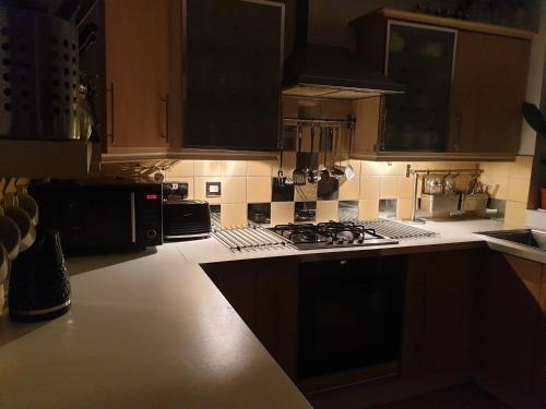 a kitchen with wooden cabinets and a stove top oven at Tropical Garden Oasis Rooms in Birmingham