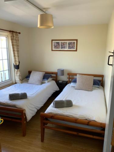 2 camas individuais num quarto com uma janela em woodpecker cottage at frog trotters cottages em Hartpury