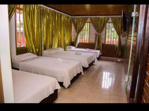 a group of three beds in a room with curtains at Finca La Gaviota in Montenegro