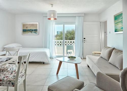 ein weißes Wohnzimmer mit einem Bett und einem Tisch in der Unterkunft So Apartments in Ayia Napa