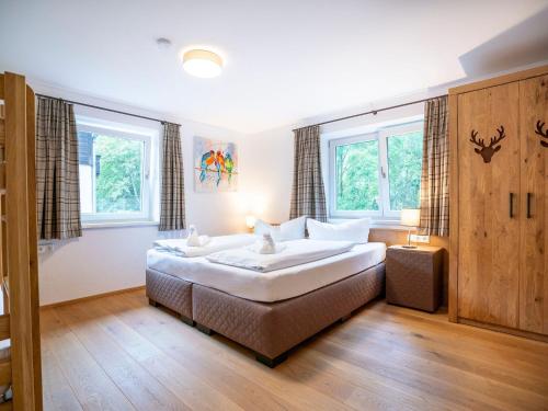 a bedroom with a large bed and two windows at Chalet in Bruck Gro glocknerstrasse with sauna in Bruck an der Großglocknerstraße