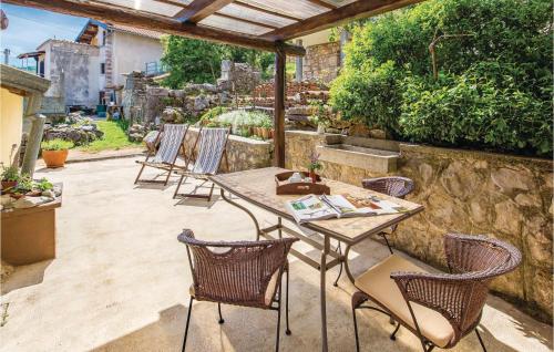 un patio con mesa, sillas y pared de piedra. en Gorgeous Home In Moscenicka Draga With Kitchen, en Mošćenička Draga