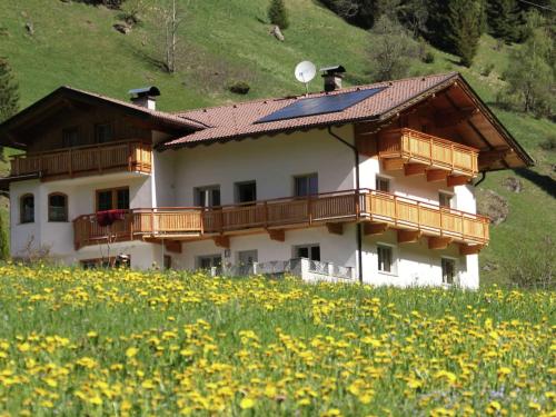 een huis op een heuvel met een bloemenveld bij A well kept holiday home full of atmosphere and with a wooden decor in Außervillgraten