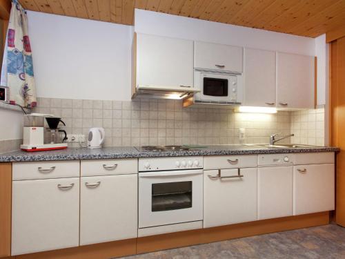 eine Küche mit weißen Schränken und einem Herd mit Backofen in der Unterkunft Apartment in Montafon near the ski area in Sankt Gallenkirch