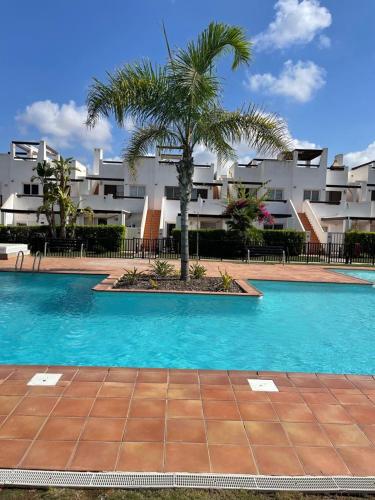 a swimming pool with a palm tree in front of a building at Casa Beau Murcia, Condado de Alhama in El Romero