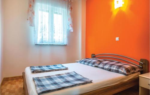 a bedroom with orange walls and a bed with two pillows at Cozy Apartment In Makarska With Kitchen in Makarska