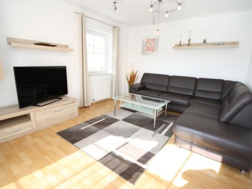 uma sala de estar com um sofá de couro preto e uma televisão de ecrã plano em Luxurious Mansion in Goldegg near Skiing Area em Goldegg
