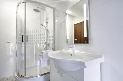 ein weißes Bad mit einem Waschbecken und einer Dusche in der Unterkunft Centrally located studio apartment Seagull in Rijeka
