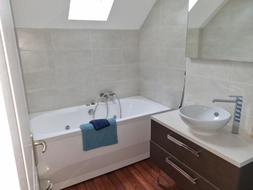 a bathroom with a white tub and a sink at Maison du port, à 100 m de la mer jusqu'à 9 personnes in Cancale
