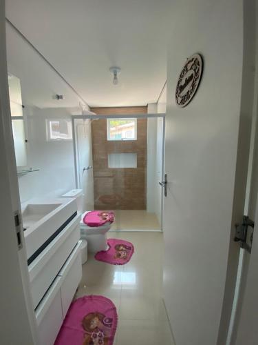 a bathroom with a toilet and pink mats on the floor at Thermas Palace in Piratuba