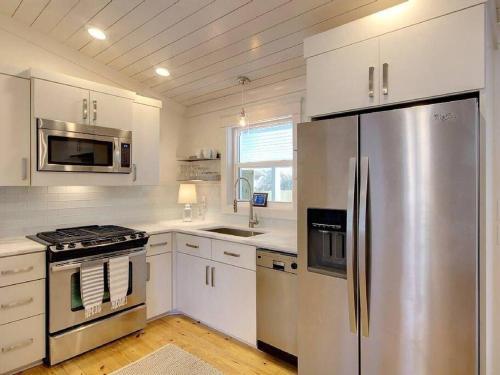 eine Küche mit weißen Schränken und einem Kühlschrank aus Edelstahl in der Unterkunft Downtown Fairhope Cottage in Fairhope