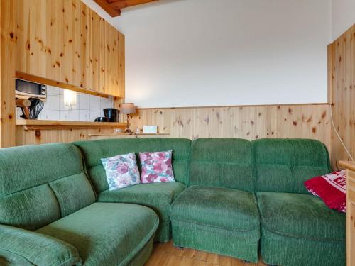 ein grünes Sofa im Wohnzimmer mit Holzwänden in der Unterkunft Cosy holiday home with private pool in Eberstein