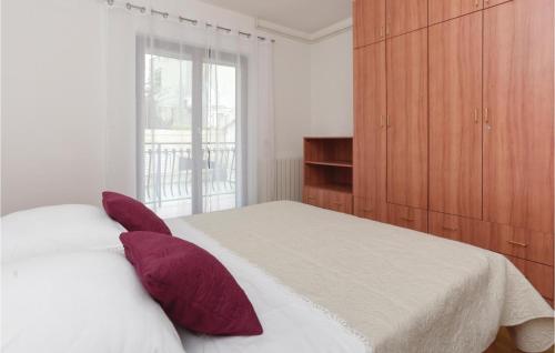 a bedroom with a bed with red pillows on it at Nice Apartment In Podstrana With 1 Bedrooms And Wifi in Podstrana